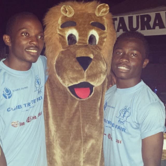 Two participants posing with a lion mascot at a community event